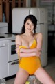 A woman in a yellow bathing suit posing for a picture.