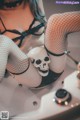 A woman in fishnet stockings sitting in a bathtub with a skull.