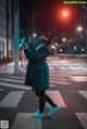 A woman wearing a cat mask standing in the middle of a street.