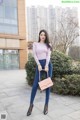 A woman in a pink top and blue jeans posing for a picture.