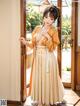 A woman in a yellow dress standing in front of a door.