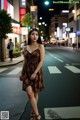 A woman in a brown dress standing in the middle of a street.