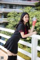 A woman in a school uniform holding a drink.