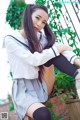 A woman in a school uniform sitting on a brick wall.