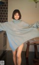 A woman in a blue sweater is posing for a picture.