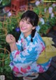 A woman in a blue and pink kimono sitting on the ground.