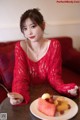 A woman sitting at a table with a plate of fruit.