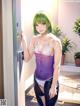 A woman with green hair standing in front of a door.