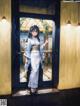 A woman in a kimono standing in front of a door.