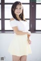 A woman in a white shirt and yellow skirt posing for a picture.