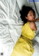 A woman in a yellow dress laying in bed.